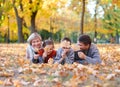 Happy family lies in autumn city park on fallen leaves. Children and parents posing, smiling, playing and having fun. Bright yello Royalty Free Stock Photo