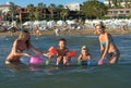 Happy family lifestyle. Young mothers with children jumping and splashing with fun in breaking waves. Summer travel, water sport