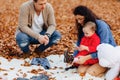 Happy family with little cute child in park on yellow leaf with Royalty Free Stock Photo