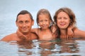 Happy family with little girl bathe in sea