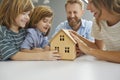 Happy family with little house model illustrating concept of mortgage and new home