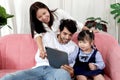 Happy family in living room, Chubby little girl daughter with her mother and father using tablet in living room. Kid spending Royalty Free Stock Photo