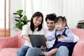 Happy family in living room, Chubby little girl daughter with her mother and father using tablet in living room. Kid spending Royalty Free Stock Photo