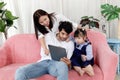 Happy family in living room, Chubby little girl daughter with her mother and father using tablet in living room. Kid spending Royalty Free Stock Photo