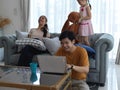 Mother using tablet and father working with laptop while daughter playing with stuffed toy on sofa in living room Royalty Free Stock Photo