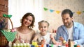 Happy family looking into camera and smiling, coloring eggs, Easter preparation Royalty Free Stock Photo