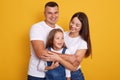 Happy family looking very excited, posing  over yellow background, mother, father and daughter wearing white shirts, woman Royalty Free Stock Photo