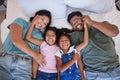 Happy family, love and morning smile with parents and children lying and playing in bed for fun together at home from Royalty Free Stock Photo