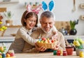 Happy family loving grandfather and cute little girl granddaughter embracing while painting Easter eggs Royalty Free Stock Photo