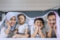 Happy family lying on bed under a blanket Royalty Free Stock Photo