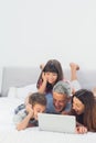 Happy family lying on bed using their laptop Royalty Free Stock Photo