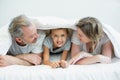 Happy family lying under blanket on bed at home Royalty Free Stock Photo