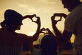 Happy family makes hands a heart sign in the evening at sunset.