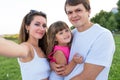 Happy family man dad woman mom, hug baby daughter and hold her arms. Taking pictures smartphone, happy joyful posing and Royalty Free Stock Photo