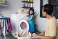 Happy family man father householder and child daughter in laundry with washing machine Royalty Free Stock Photo