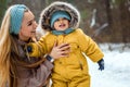 Happy family mom and baby sy on a winter walk in the forest. Concept for christmas, family, relatives, vacations, fresh air Royalty Free Stock Photo