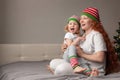 happy family mom and child sitting bed New Year hats shouting surprised, copy space, concept Christmas, discounts, sales