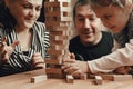 Happy family mom dad and daughter spend free time playing Jenga board game