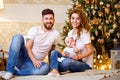 Happy family of mom, dad and little baby girl sitting near Christmas tree on the floor Royalty Free Stock Photo