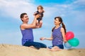 Happy family, mom, dad and little son in striped vests having fun in the sand outdoors against blue sky background. Summer Royalty Free Stock Photo