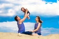 Happy family, mom, dad and little son in striped vests having fun in the sand outdoors against blue sky background. Summer Royalty Free Stock Photo