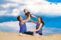 Happy family, mom, dad and little son in striped vests having fun in the sand outdoors against blue sky background. Summer Royalty Free Stock Photo