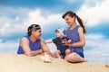 Happy family, mom, dad and little son in striped vests having fun in the sand outdoors against blue sky background. Summer Royalty Free Stock Photo