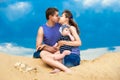 Happy family, mom, dad and little son in striped vests having fun in the sand outdoors against blue sky background. Summer Royalty Free Stock Photo