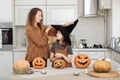 Happy family: mom and daughter celebrate Halloween. Merry child in witch carnival costume in the room. Cheerful kid and Royalty Free Stock Photo