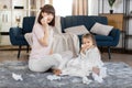 Happy family mom and daughter, having fun together at home, wiping faces with paper napkins. Young mother sitting on the