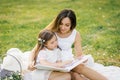 Happy family mom and daughter are watching an album with photos in the summer Royalty Free Stock Photo