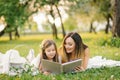 Happy family mom and daughter are watching an album with photos in the summer in the park or in the garden Royalty Free Stock Photo