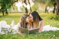 Happy family mom and daughter are watching an album with photos in the summer in the park or in the garden Royalty Free Stock Photo