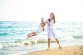 Happy family mom and little daughter play and fool around the coast on sea beach at resort