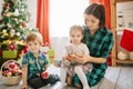 Happy family mom, son and daughter on a Christmas winter sunny morning in a decorated Christmas celebration room with a Royalty Free Stock Photo