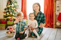 Happy family mom, son and daughter on a Christmas winter sunny morning in a decorated Christmas celebration room with a Royalty Free Stock Photo