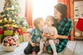 Happy family mom, son and daughter on a Christmas winter sunny morning in a decorated Christmas celebration room with a Royalty Free Stock Photo