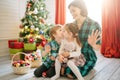 Happy family mom, son and daughter on a Christmas winter sunny morning in a decorated Christmas celebration room with a Royalty Free Stock Photo