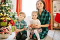 Happy family mom, son and daughter on a Christmas winter sunny morning in a decorated Christmas celebration room with a Royalty Free Stock Photo