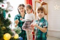 Happy family mom, son and daughter on a Christmas winter sunny morning in a decorated Christmas celebration room with a Royalty Free Stock Photo