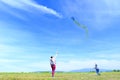 Happy family, mom and son, playing with flying kite on meadow in beautiful spring sunny day, blue sky in background Royalty Free Stock Photo