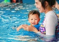 Happy family of mom teaching baby boy in swimming pool Royalty Free Stock Photo