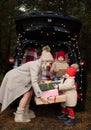 Happy family of mom and two kids with Christmas gift boxes sitting in christmas decorated car Royalty Free Stock Photo