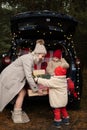 Happy family of mom and two kids with Christmas gift boxes sitting in christmas decorated car Royalty Free Stock Photo