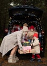 Happy family of mom and two kids with Christmas gift boxes sitting in christmas decorated car Royalty Free Stock Photo