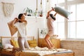 Its a battle. Excited happy older and younger sister fighting with pillows in bedroom, laughing and having fun together Royalty Free Stock Photo