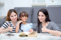 Happy family mother, aunt, freind and daughter teaching read a b Royalty Free Stock Photo