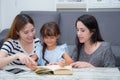 Happy family mother, aunt, freind and daughter teaching read a book at home.