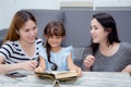 happy family mother, aunt, freind and daughter teaching read a book. Royalty Free Stock Photo