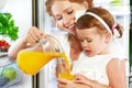 Happy family mother and baby daughter drinking orange juice in Royalty Free Stock Photo